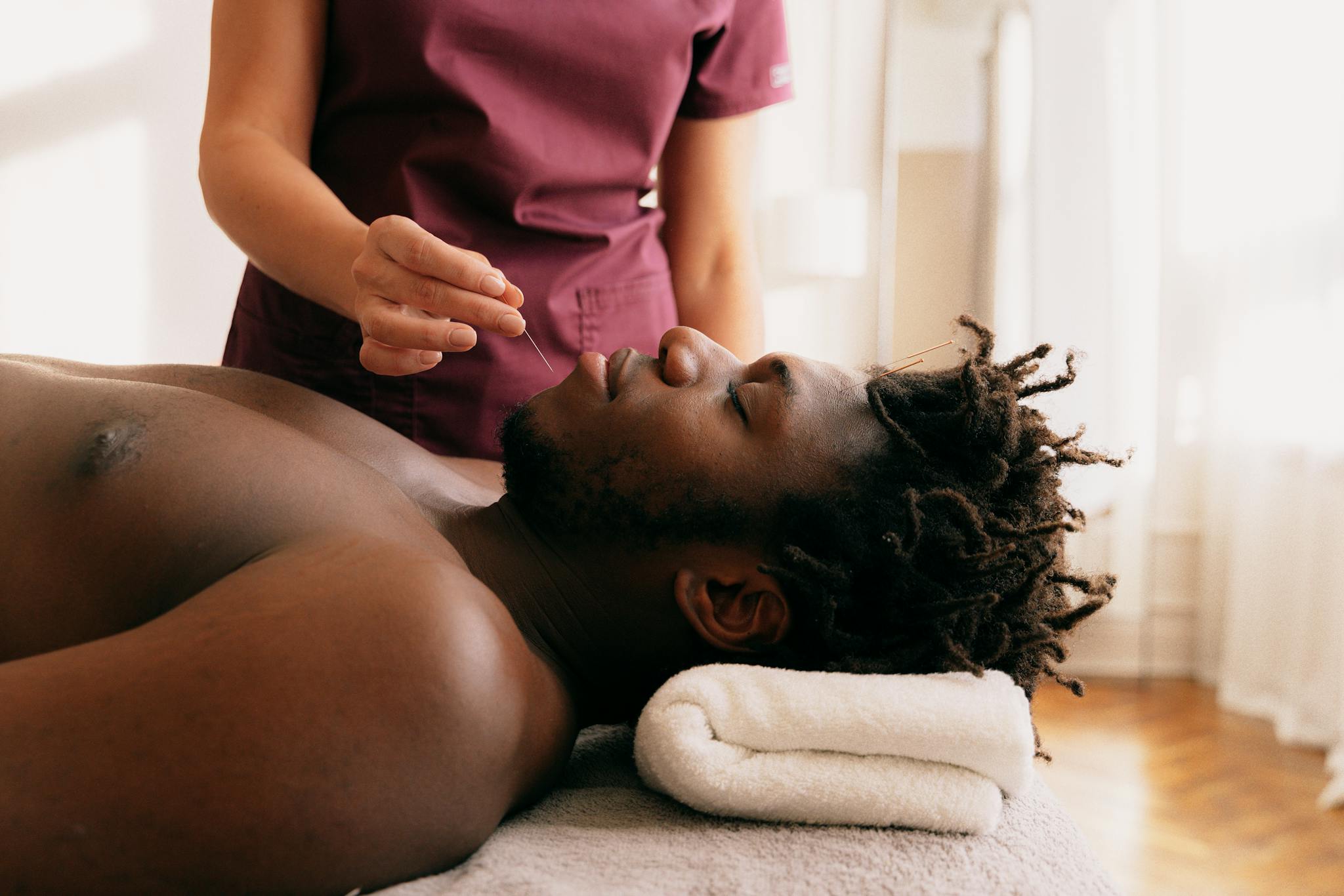 Acupuncture treatment on a relaxed man performed by a therapist in a serene setting.